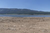 there is a body of water surrounded by mountains and rocks and dirt field, with a man on a bench in the foreground