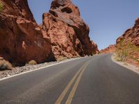 a view of a narrow canyon road going by it and there are rocks and bushes