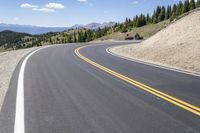 a long curved highway with mountain views in the background and people riding down it at each end