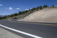 a long curved highway with mountain views in the background and people riding down it at each end