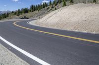 a long curved highway with mountain views in the background and people riding down it at each end