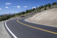 a long curved highway with mountain views in the background and people riding down it at each end