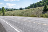 an open road is shown with a mountain in the background with trees on one side and hills on the other, near a highway