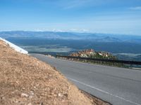 a man is riding his bike down a mountain road with snow and rocks in the background