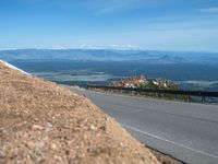 a man is riding his bike down a mountain road with snow and rocks in the background