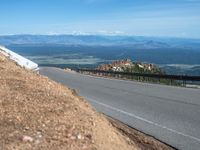 a man is riding his bike down a mountain road with snow and rocks in the background