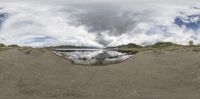 a panoramic view of a lake with sand around it and water coming from the bottom