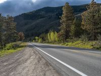 a person on a bike rides down the road with mountains in the distance along side of it