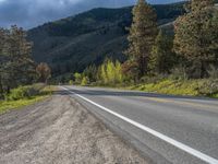 a person on a bike rides down the road with mountains in the distance along side of it