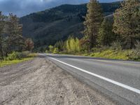 a person on a bike rides down the road with mountains in the distance along side of it