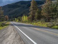 a person on a bike rides down the road with mountains in the distance along side of it