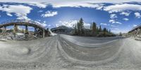 a photo of a large train on a track surrounded by mountains and trees, on a panorama fisheye