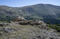 the rocks and green trees are next to the hill, on top of a mountain