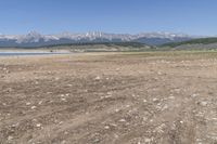 an open land with rocky mountains in the distance, with a blue sky over the valley