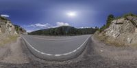 the 360 - view image of a road winding through mountains and rocks in front of a sunny sky