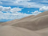 a person rides on a horse in a large desert area under blue skies with white clouds