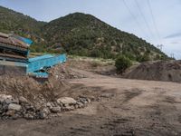 two yellow bulldozers work on sand and gravel in a mountain valley while another one looks at it