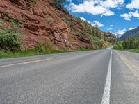 the red rocks are high up on the side of the road and it is an amazing color