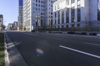the sun is shining in an empty street near several tall buildings and a car on the road