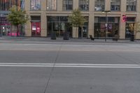 a empty city street next to a big building with tall windows on top of it