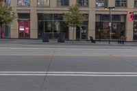 a empty city street next to a big building with tall windows on top of it