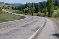 a lone motorcycle travels along a curvy road in the country mountains and meadows