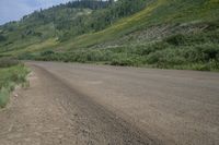 a motorcyclist taking in the scenery on a dirt road next to a hill