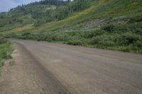 a motorcyclist taking in the scenery on a dirt road next to a hill