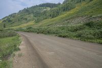 a motorcyclist taking in the scenery on a dirt road next to a hill