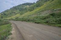 a motorcyclist taking in the scenery on a dirt road next to a hill