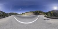 a fish - eye view looking down an empty highway into the mountains at dusk,