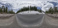 fish eye lens view of a mountain highway in winter with snow and clouds above it