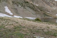 the man with his dog is hiking through the mountains and looks back at the water