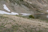 the man with his dog is hiking through the mountains and looks back at the water