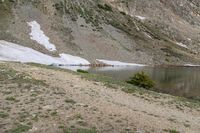 the man with his dog is hiking through the mountains and looks back at the water