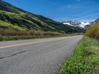 the road is paved with yellow markings and has a snowy mountain range in the background