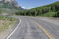 the motorcycle is parked on the empty street next to the mountains, and there's a yellow and blue sign pointing up for the bikers