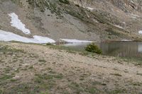 a body of water in the mountains next to snow covered slopes with a boat docked on the shore