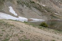 a body of water in the mountains next to snow covered slopes with a boat docked on the shore