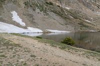 a body of water in the mountains next to snow covered slopes with a boat docked on the shore