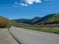 the road is paved with yellow markings and has a snowy mountain range in the background