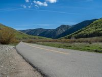 the road is paved with yellow markings and has a snowy mountain range in the background