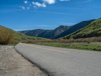 the road is paved with yellow markings and has a snowy mountain range in the background