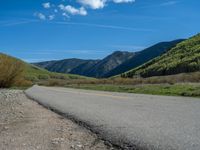 the road is paved with yellow markings and has a snowy mountain range in the background