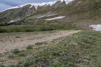 there is an open area with snow on the mountains behind it and a trail leading towards the camera