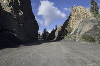 rock formation near the side of a mountain near pine trees near road, outdoors in outdoor
