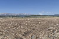 an open field with some rocks and mountain range in the background and a car in the middle