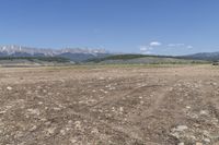 an open field with some rocks and mountain range in the background and a car in the middle