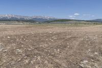 an open field with some rocks and mountain range in the background and a car in the middle