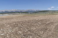 an open field with some rocks and mountain range in the background and a car in the middle